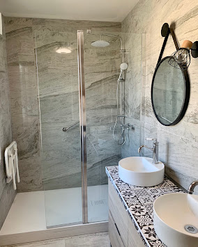 Salle de bains avec douche vitrée, carrelage clair et meuble lavabo en bois